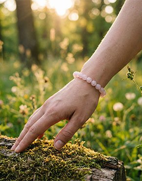 Woman wearing a Rose Quartz bracelet outdoors in soft natural sunlight
